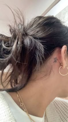 the back of a woman's head with a small tattoo on her left ear