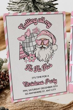 a pink and white christmas party card with santa clause on it's face, sitting next to a pine tree