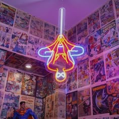 a room filled with comic books on the wall and a neon light hanging from the ceiling