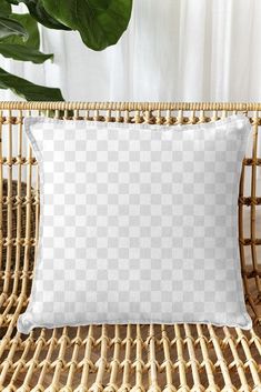 a white pillow sitting on top of a wicker chair next to a potted plant