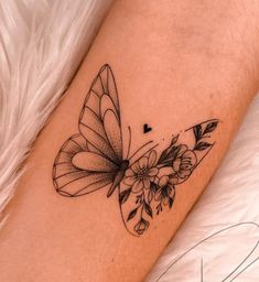 a small butterfly tattoo on the arm with flowers and leaves around it's wings