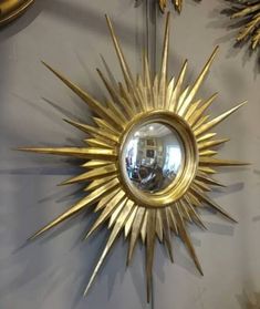 a gold sunburst hanging on the wall with mirrors in it's center