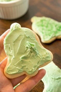 someone is holding up some green frosted cookies