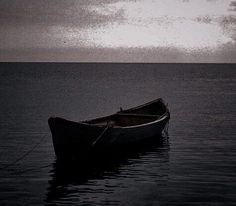 a small boat floating on top of a body of water under a gray cloudy sky