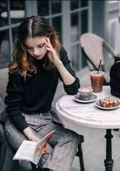 a woman sitting at a table reading a book