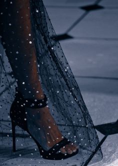 a woman's feet in high heels on the runway with water droplets all over them