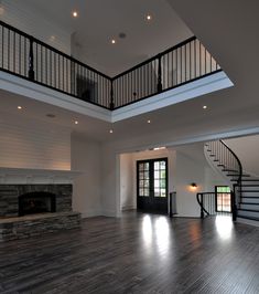 an empty living room with wood floors and stairs