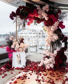 an outdoor ceremony with flowers and petals on the ground, next to a photo frame