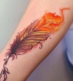 an orange and black feather tattoo on the left arm with watercolor splashes around it