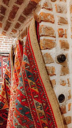 several colorful rugs are hanging on a brick wall