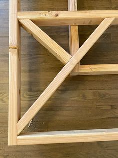 an unfinished wooden shelf on top of a hard wood floor with nails sticking out of it