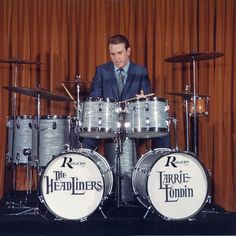 a man in a suit and tie playing drums