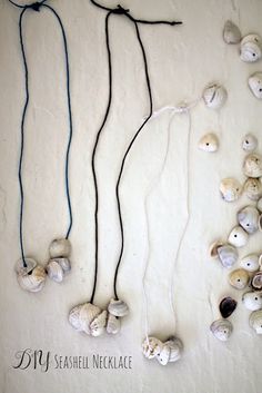 three seashell necklaces are displayed on a white surface with black string and beads