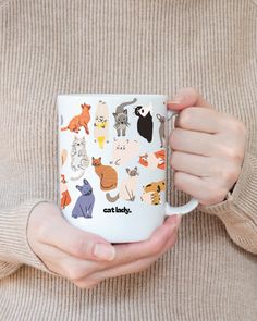 a person holding a coffee mug with cats on it