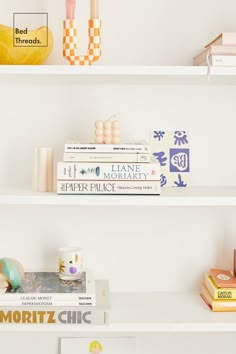 three white shelves with books and other items on top of each shelf in front of a banana