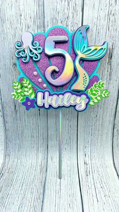 a cake topper with the number five on it and an image of a mermaid tail