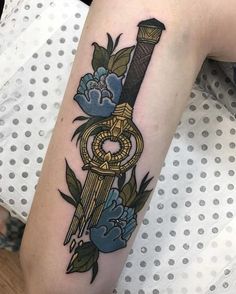 a woman with a tattoo on her arm holding a key and flower bouquet in it