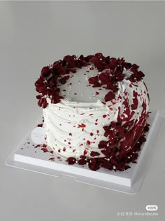 a large white cake with red flowers on it's top and bottom layer is covered in icing