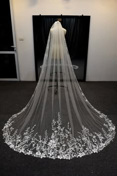 a wedding veil with white flowers on the bottom is shown in front of a black backdrop