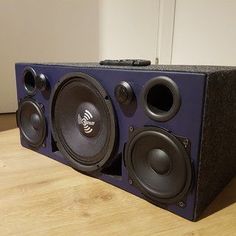 a speaker sitting on top of a wooden table next to a wall mounted subwoofer