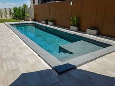 an empty swimming pool in the middle of a patio with potted plants on either side