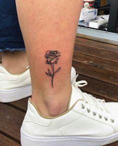 a woman's foot with a small rose tattoo on the left side of her leg