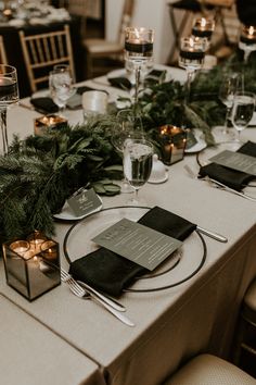 the table is set with place settings, candles and greenery for an elegant dinner