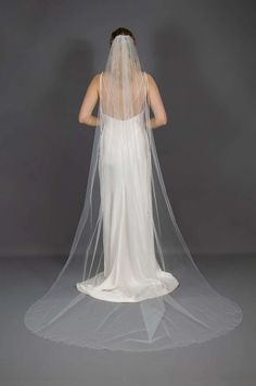 the back of a woman's wedding dress with a long veil