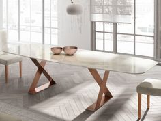 a table with two bowls on it in front of a window and some white chairs