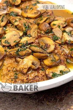 a casserole dish with mushrooms and herbs in gravy on a table