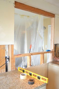 a kitchen being remodeled with tools on the counter top and walls covered in plastic sheeting