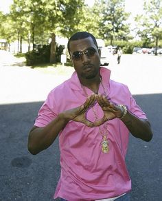 a man in a pink shirt is holding his hands up to spell the word love