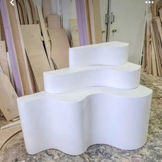 three white curved tables sitting on top of a marble floor next to bags and boxes