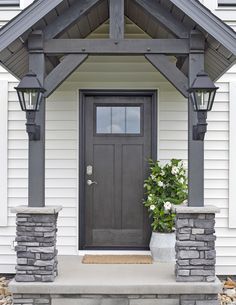 a black front door on a white house with stone steps and planters in the foreground