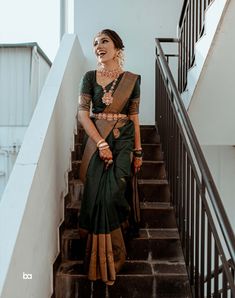 a woman in a green sari standing on some stairs with her hand on her hip