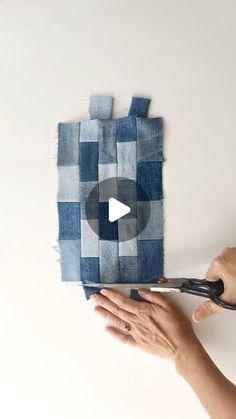 someone using scissors to cut fabric on top of a piece of blue and white material