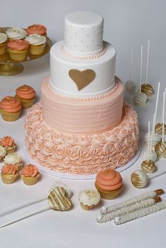 a three tiered cake surrounded by cupcakes and candy