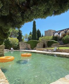 an outdoor swimming pool with inflatable floats floating on it's sides and trees