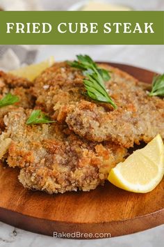 fried cube steak on a cutting board with lemon wedges