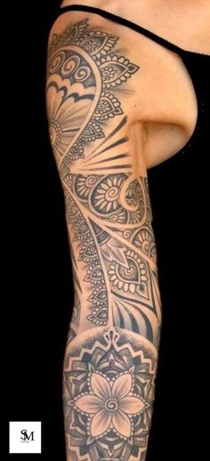 a woman's arm with tattoos on it and an intricate flower design in the middle