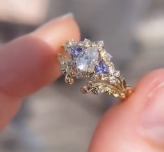 a close up of a person's hand holding a diamond and tan sapphire ring