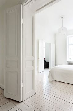 an open door in the middle of a room with white walls and wood flooring