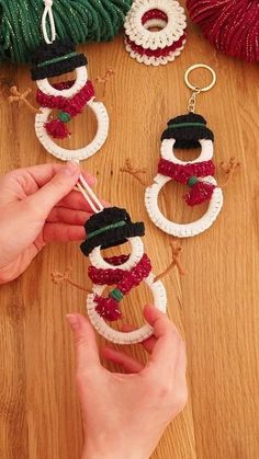 handmade snowman ornament being held up by someone's hands on a wooden table