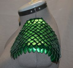 the back of a mannequin's torso with green and silver scales on it