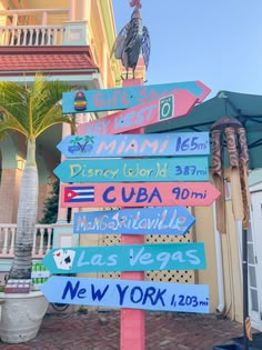 a street sign with many different colored signs on it's post in front of a building