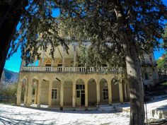 an old building with columns and arches on the outside, in front of some trees