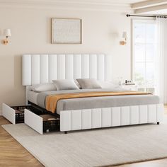 a white bed with two drawers underneath it in a room next to a large window