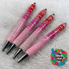 four pink and red pens sitting on top of a white blanket next to each other