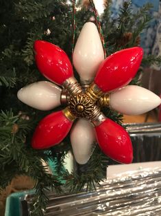 a red and white flower ornament hanging from a christmas tree