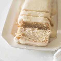 a white plate topped with slices of cake covered in frosting on top of a table